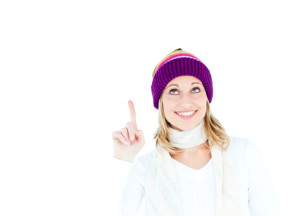 Young caucasian woman wearing a colorful hat pointing upwards wi
